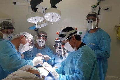 Foto da mesa de operação com o Dr. Raul e outros médicos e enfermeiros operando uma pessoa
